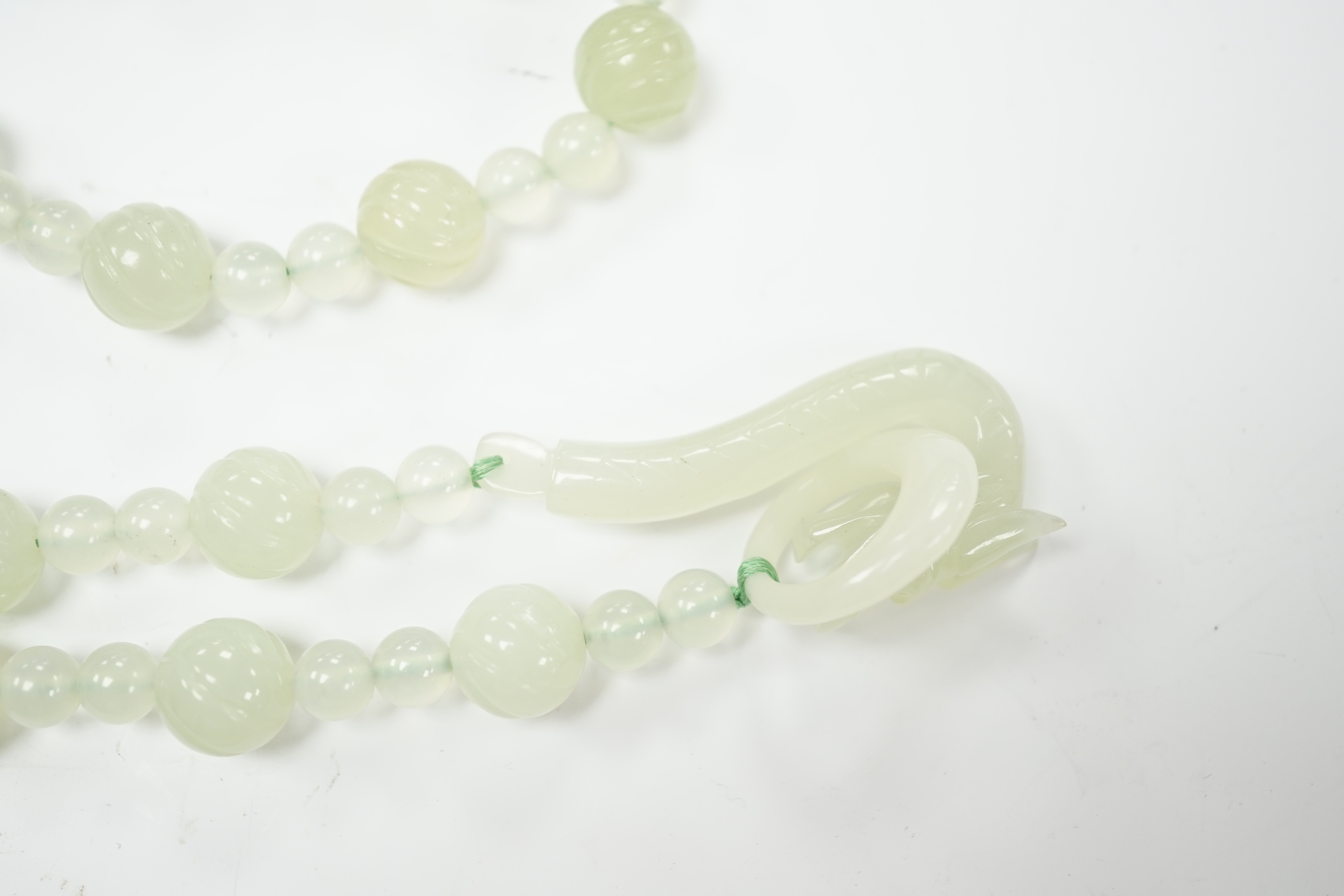 A bowenite jade bead necklace with dragon head clasp, circular pendant and carved disc